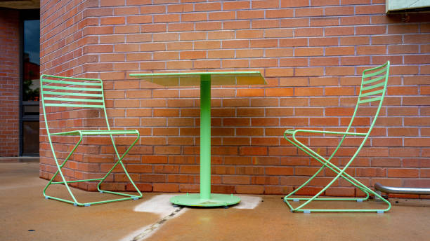 istock Green table and chairs with a brick building wall 1497674126