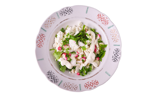 Vegetable salad from the garden. Watercress salad and white and red radish cut in a plate with colorful ornament, white cheese and sour cream, isolate, fresh, natural, top view