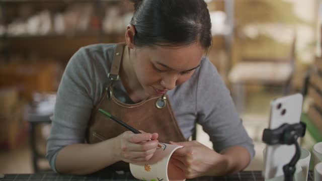 Young woman making handmade ceramics in her pottery workshop, small business concept