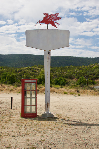 Abandoned telephone booth and vintage sign in the desert