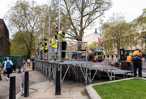 A line of men who are dismantling a viewing stand which had been used for the Coronation of King Charles III the previous day. A major clean-up was underway in The Mall and nearby streets.