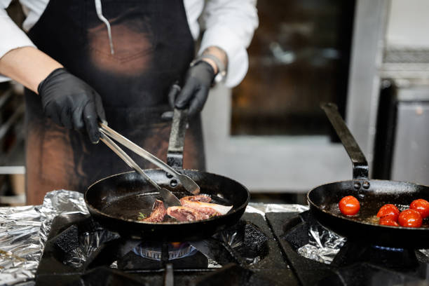 Closeup of professional male chef cooking octopus with shrimps in the commercial kitchen