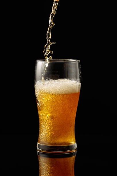 istock Pouring beer into a glass on a black reflective background. 1497682222