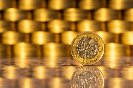 A British pound coin with many gold coins in the background