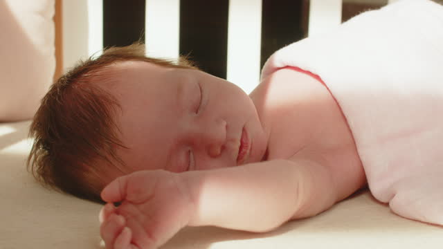 Cute newborn baby girl waking up in her crib