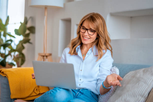 istock Happy mid aged woman using her laptop at home 1497685559