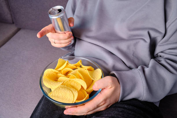 istock A man eats crispy potato chips from a transparent bowl on the couch. Quick snack. Calories and diet. Junk food 1497686647
