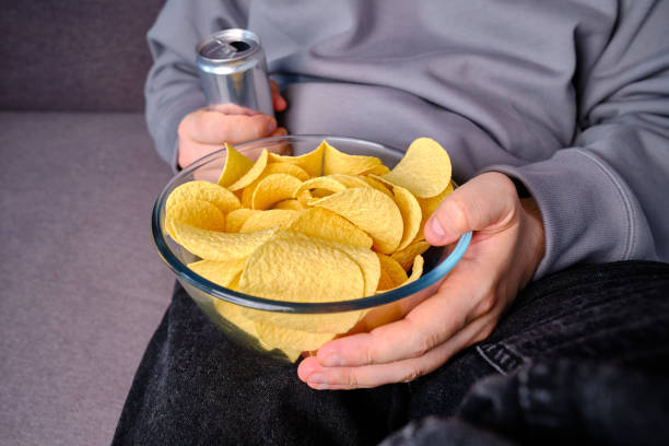 istock A man eats crispy potato chips from a transparent bowl on the couch. Quick snack. Calories and diet. Junk food 1497686649