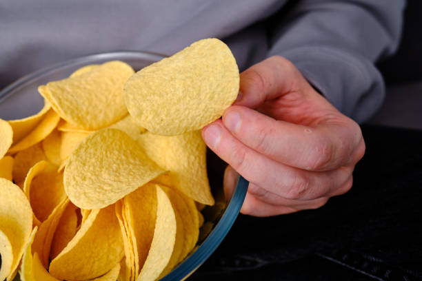 istock A man eats crispy potato chips from a transparent bowl on the couch. Quick snack. Calories and diet. Junk food 1497686662