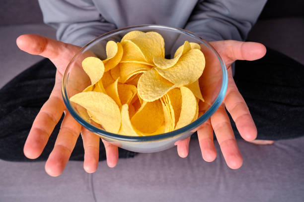 istock A man eats crispy potato chips from a transparent bowl on the couch. Quick snack. Calories and diet. Junk food 1497686666