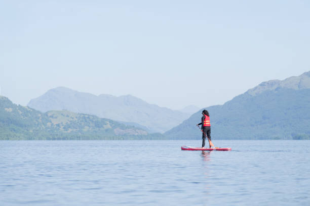 Loch Lomond, Scotland, UK, June 4th 2023, Single female on a stand up paddle board during a summer morning