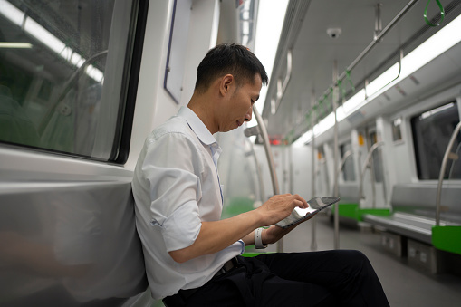 Asian man using tablet on subway