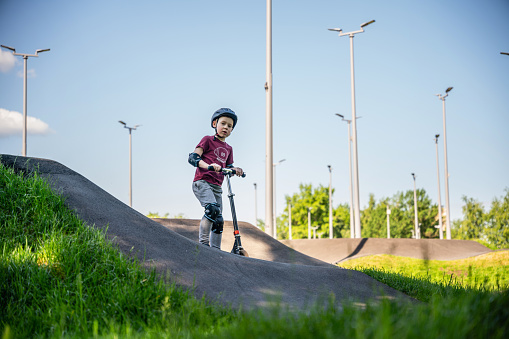 Boy with a push scooter at the outdoors pump-track