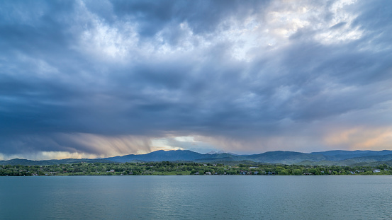 dramatic storm clouds at dusk over Rocky Mountains and lake in northern Colorado