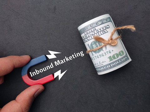 A hand holding magnet to attracts banknotes with word Inbound Marketing - Business concept