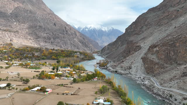 Scenic aerial view of Gilgit river in Karakoram Range in Himalayas mountains along Karakoram Highway with small village in autumn. Gupis Province Northern Pakistan