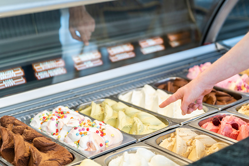 Close-up of a Scene with somebody choosing a flavor of ice cream in a store with a female assistant