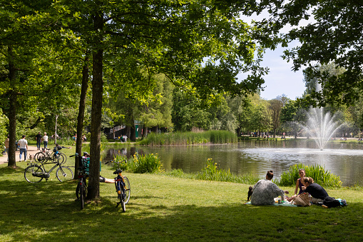 Amsterdam, Netherlands, May 28, 2023; Residents and tourists enjoy the beautiful weather on a lawn near the water in the Vondelpark.