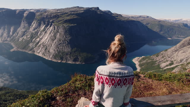 Female hiker contemplating spectacular views from her tent, wild camping in Norway