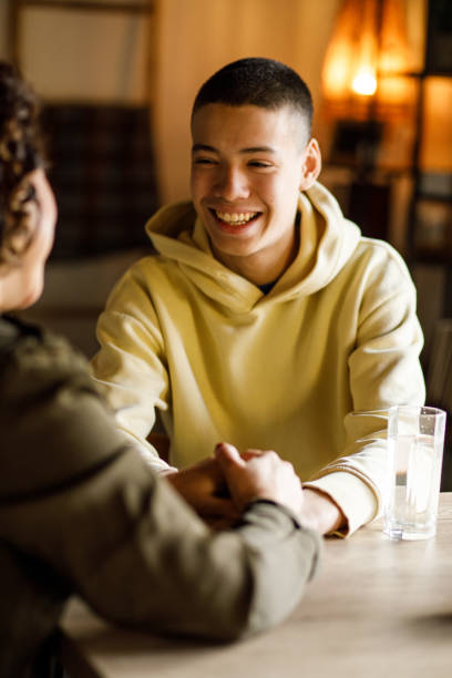 Caring mother gently caressing teenage son's face and giving heartfelt advice stock photo