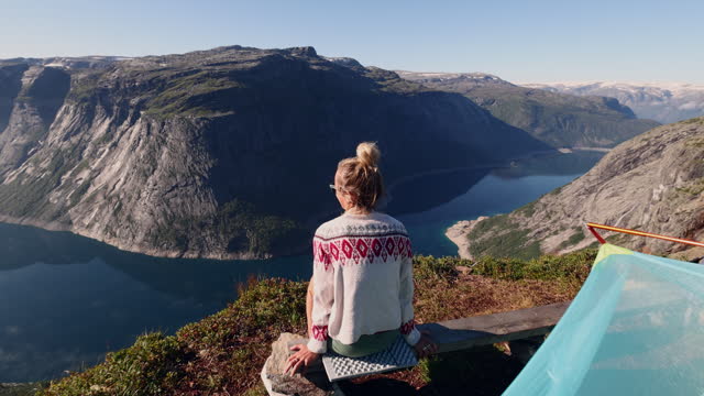 Female hiker contemplating spectacular views from her tent, wild camping in Norway