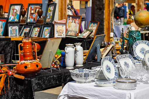 Nice, France - April 24, 2023: Many old porcelain objects, glassware and other objects are displayed for sale in one of the stalls at the famous flea market known as Cours Saleya.