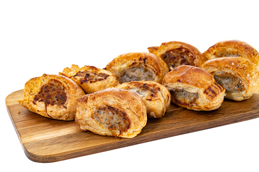 Mini cocktail sausage rolls on a wood platter - white background