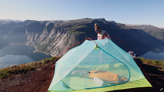 Woman setting up tent outdoors in Norway, spectacular view