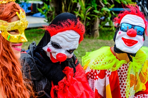 Salvador, Brazil – February 28, 2017: Three cheerful masked people in colorful costumes during a carnival in Salvador