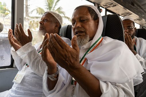 Guwahati, India. 7 June 2023.  Hajj pilgrims offer Namaz or prayers inside a bus before leaving to the airport for Mecca, on June 7, 2023 in Guwahati, India.