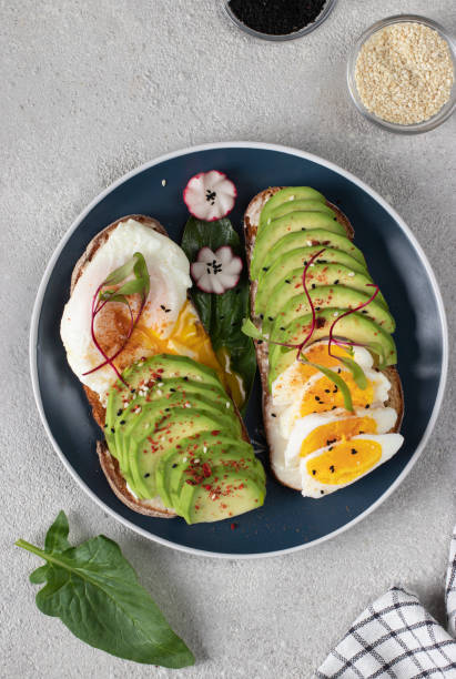 istock Healthy breakfast - sandwiches with avocado, egg and sesame on round plate on gray table, Top view 1497708482