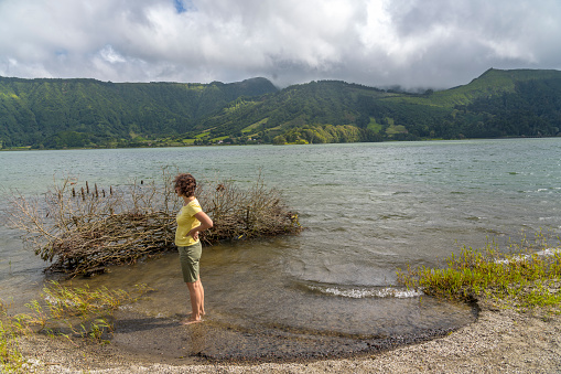 The lake Furnas is situated in a very active volcanic activity. One women standing in the water close to the beach.