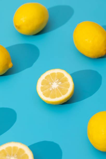 istock Juicy yellow lemons on a blue background with hard shadows. Summer pattern with ripe lemons. 1497718054