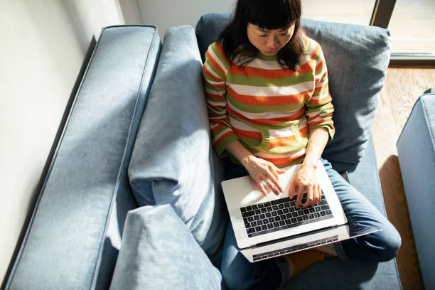 istock Young Japanese Woman using a laptop at home on the couch 1497719116