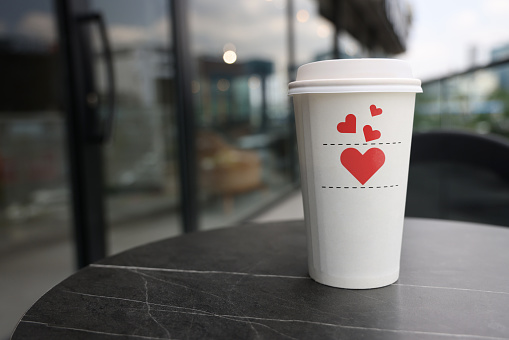 Heart shape coffee cup over red background. View from above