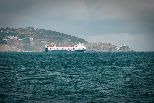 Dublin, Ireland - March 2023 - A seatruck ship passing by Howth, with Howth Lighthouse and the Irish Sea visible