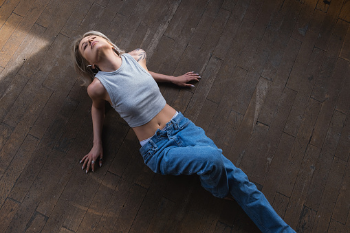 Beautiful young blonde woman lying on the wooden floor.