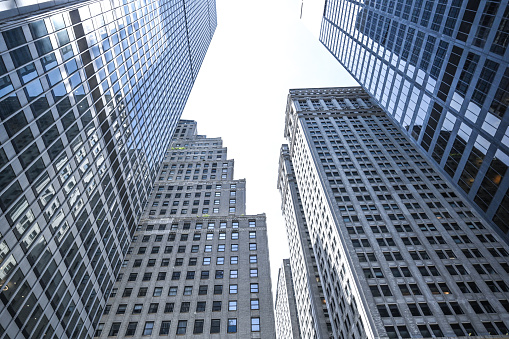 Side view on modern stylish business center building with panoramic windows reflecting the city skyline on light sky background. 3D rendering