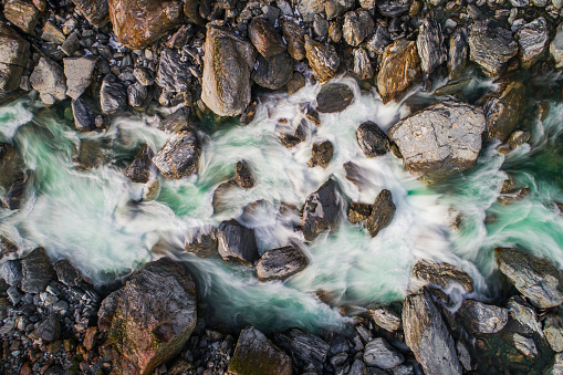 Directly above looking down at rushing rapid river from snowmelt in the mountains. Photographed using slow shutter motion blur in New Zealand.