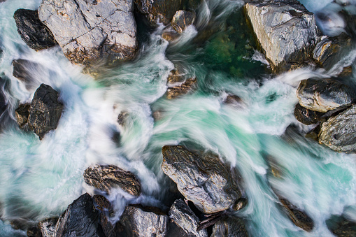 Directly above looking down at rushing rapid river from snowmelt in the mountains. Photographed using slow shutter motion blur in New Zealand.