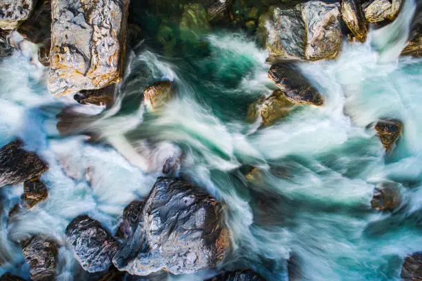 Directly above looking down at rushing rapid river from snowmelt in the mountains. Photographed using slow shutter motion blur in New Zealand.