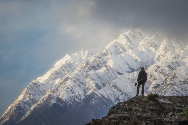 istock Young professional man with camera equipment contemplating dramatic mountain landscape 1497732028