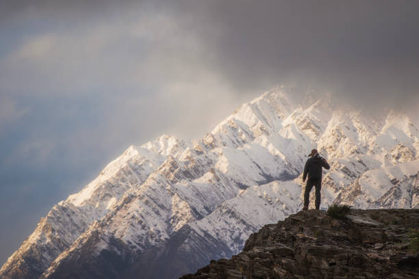 istock Young professional man with camera equipment contemplating dramatic mountain landscape 1497732032