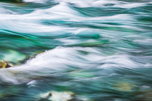 Rushing rapid river from snowmelt in the mountains. Photographed using slow shutter motion blur in New Zealand.