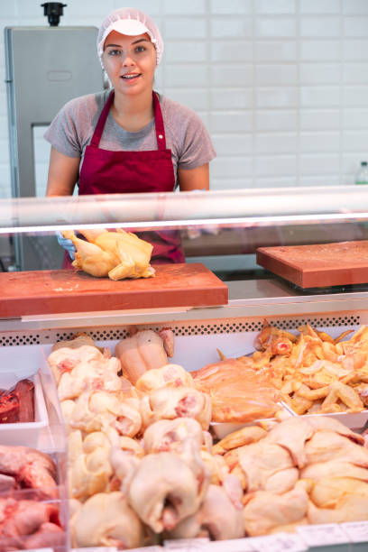 istock Young saleswoman laying raw broiler chickens in display case 1497732417