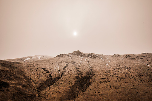 Looking up a mountain at sun shining through foggy atmospheric environment