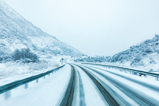 Driving along a snow covered winter road in a blizzard