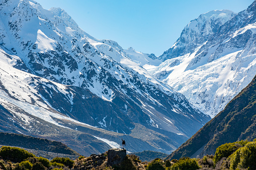 Nature scene of man looking at awe-inspiring snow covered mountain. Photographed in New Zealand.