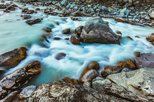 Flowing water over rocks in glacial melt river in the mountains of New Zealand.