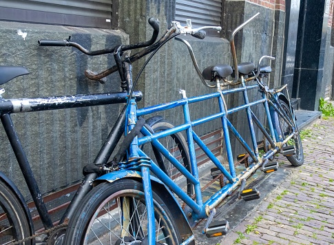 Bicycles parked against a red brick wall, a third bicycle securely locked in front